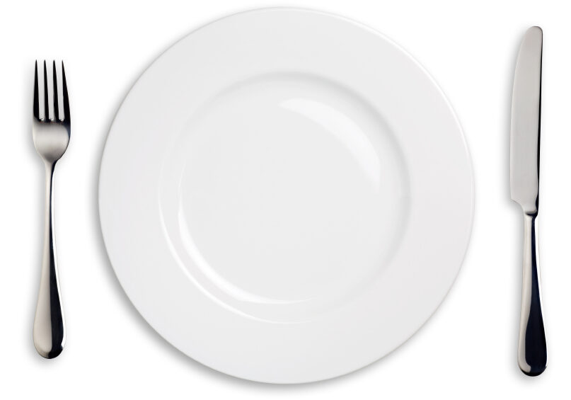 A white china plate with silver knife and fork.  Isolated on white with clipping paths.